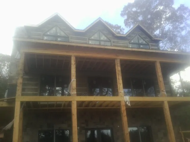 Dormers and porch framing on a large log home under construction — Roof Coating work by our crew in Roan Mountain
