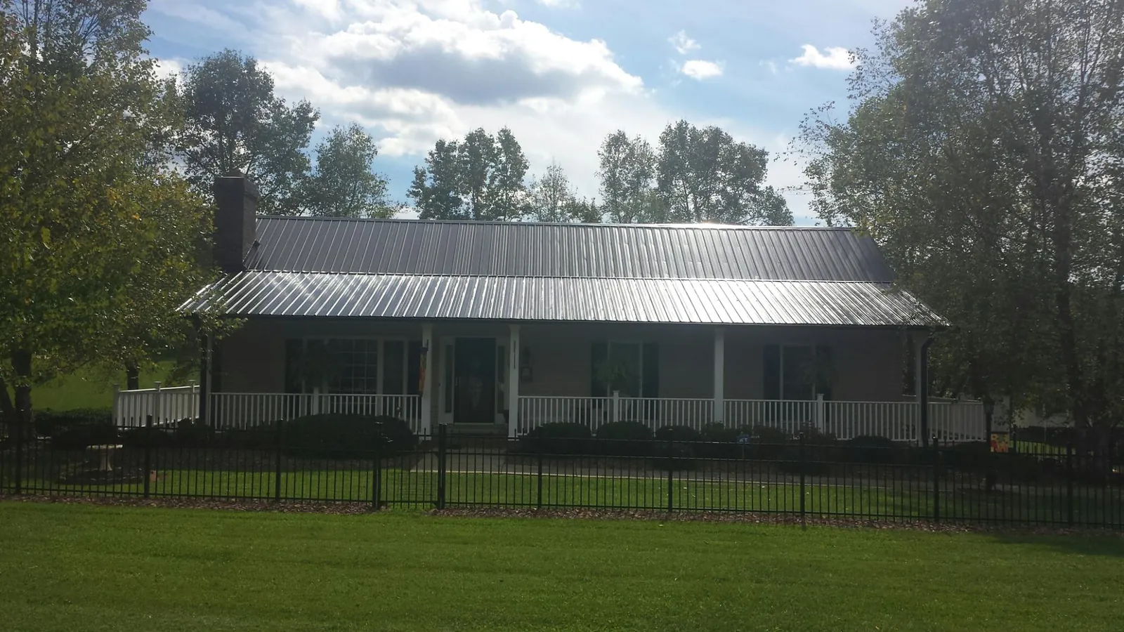 Gray metal roof on a brick ranch with a full width front porch in Roan Mountain