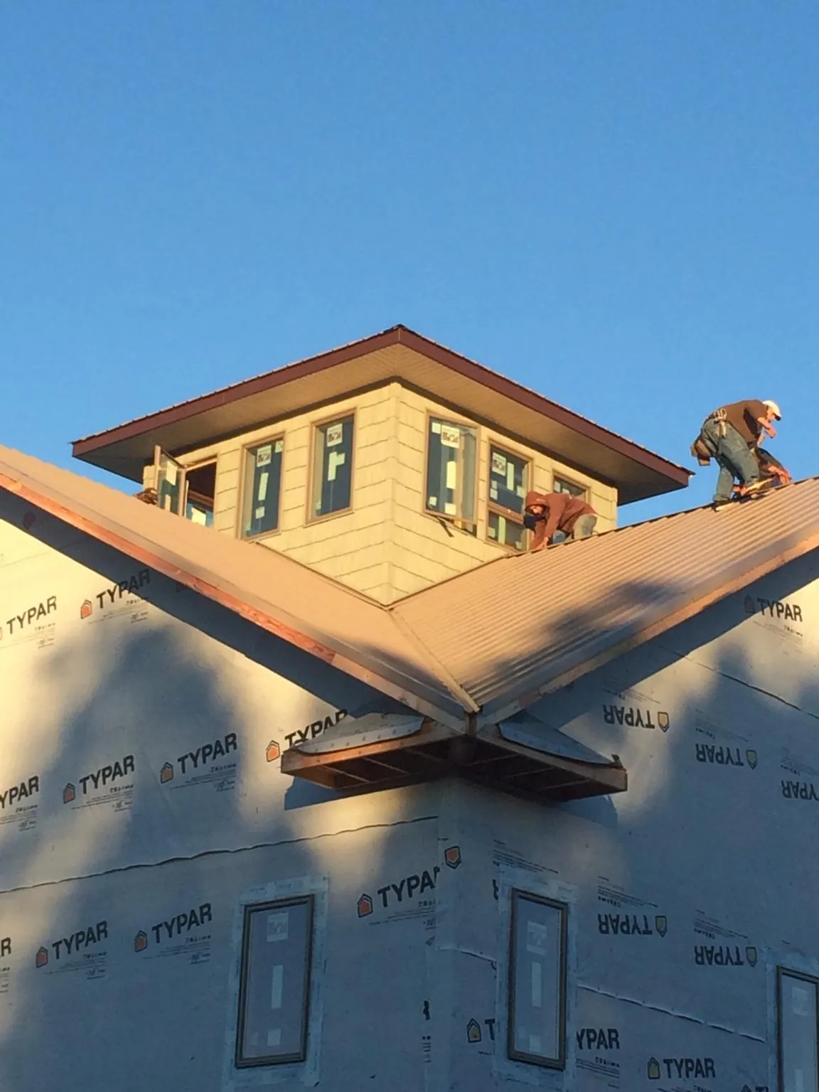 Roofers working around a rooftop cupola on a new metal roof at sunset — Roof Waterproofing in Roan Mountain by Roofing Brothers